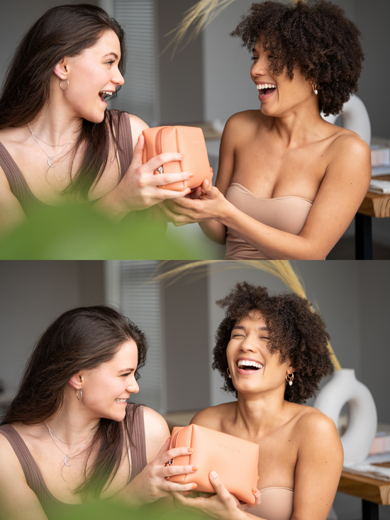 2 young ladies laughing and holding a beauty bag